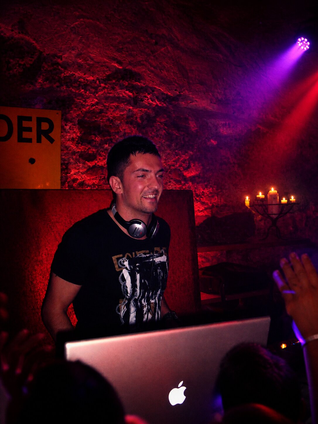 DJ Marseille dans une cave voûtée éclairée en rouge, ambiance intime aux chandelles