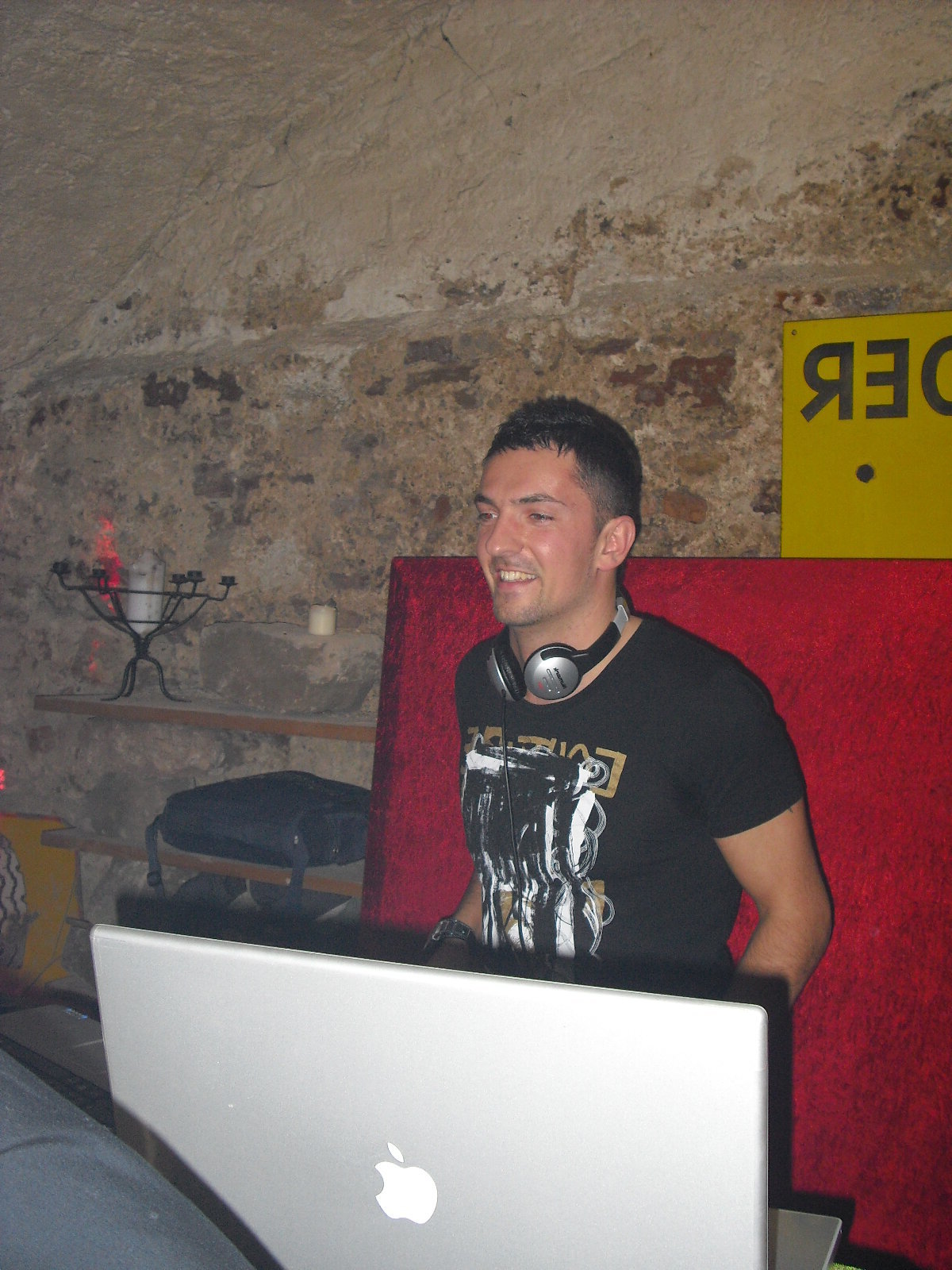 DJ Marseille souriant aux platines dans une cave voûtée en pierre